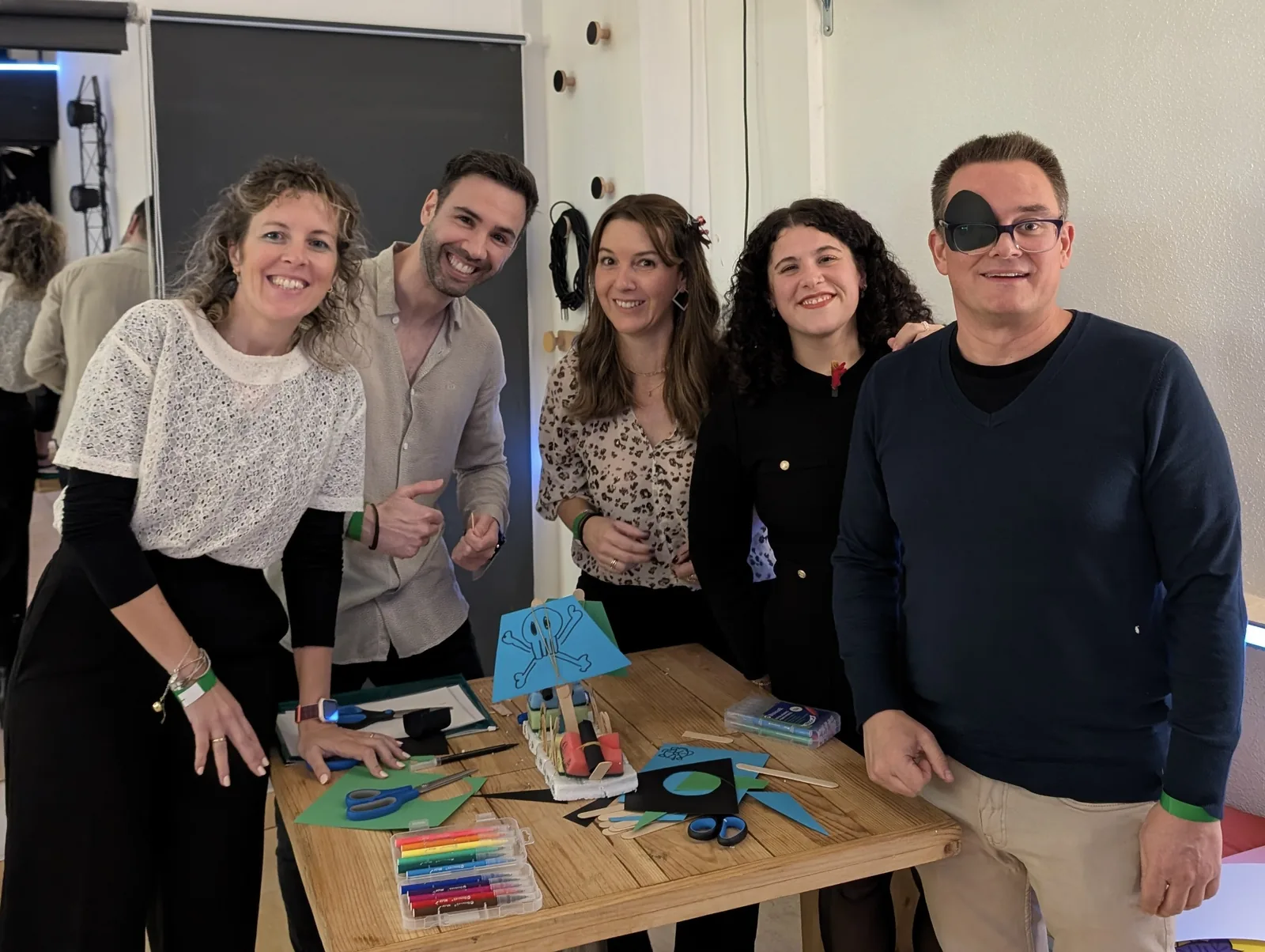 Equipo de empresa sonriendo junto al barco pirata corporativo construido en el team building Abordaje Pirata de Froggy Events