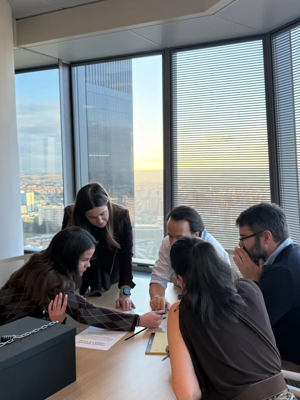 Equipo abriendo la caja del escape room portátil Operación Parallax con vistas a Madrid