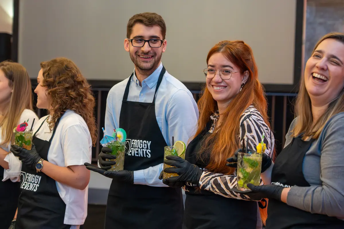 Participantes con delantales Froggy Events elaborando cócteles en el taller de coctelería corporativa