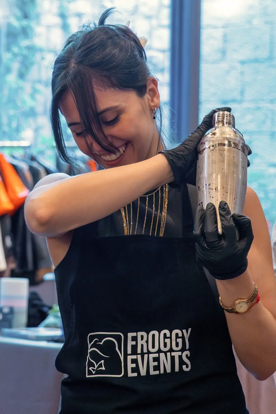 Participante con delantal Froggy Events agitando el shaker en el taller de coctelería para empresas Master Cóctel