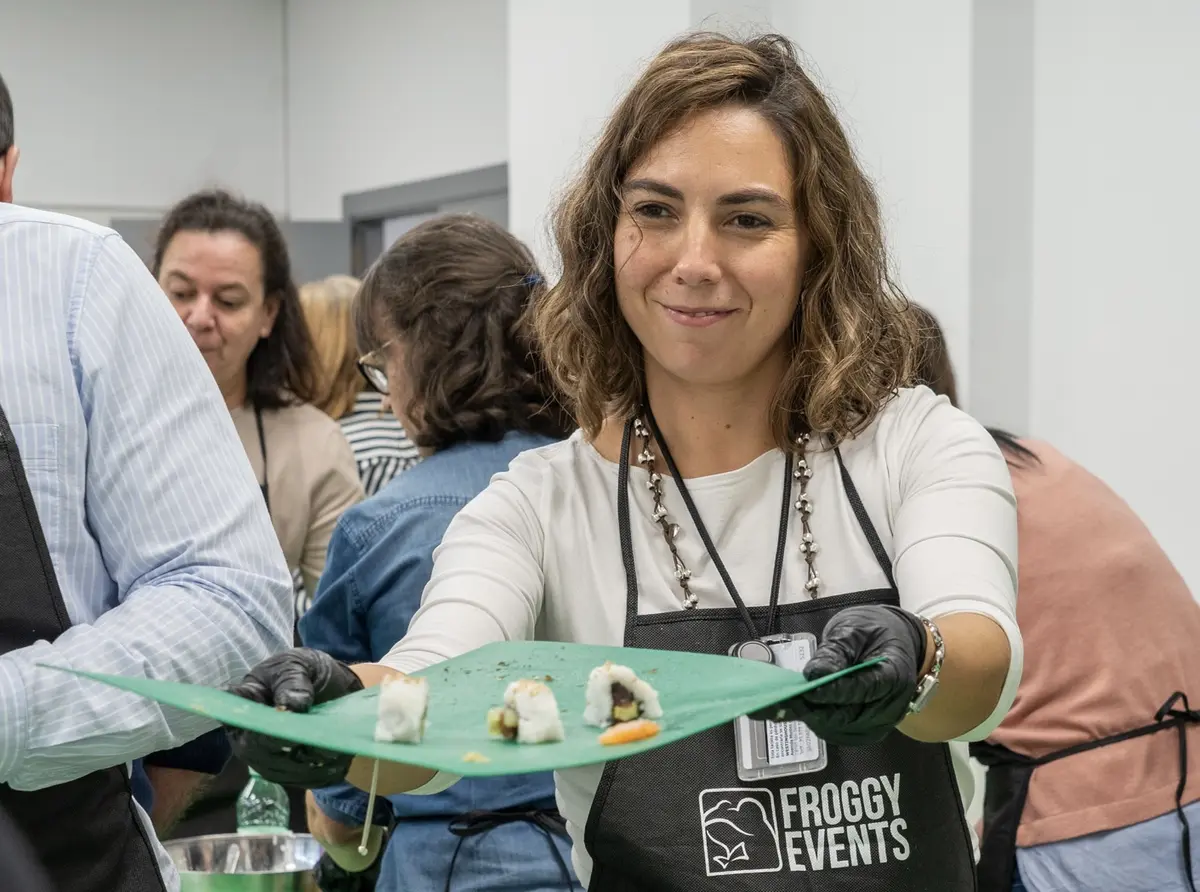 Participante con delantal Froggy Events mostrando sus piezas de sushi en el taller de sushi para empresas Master Sushi