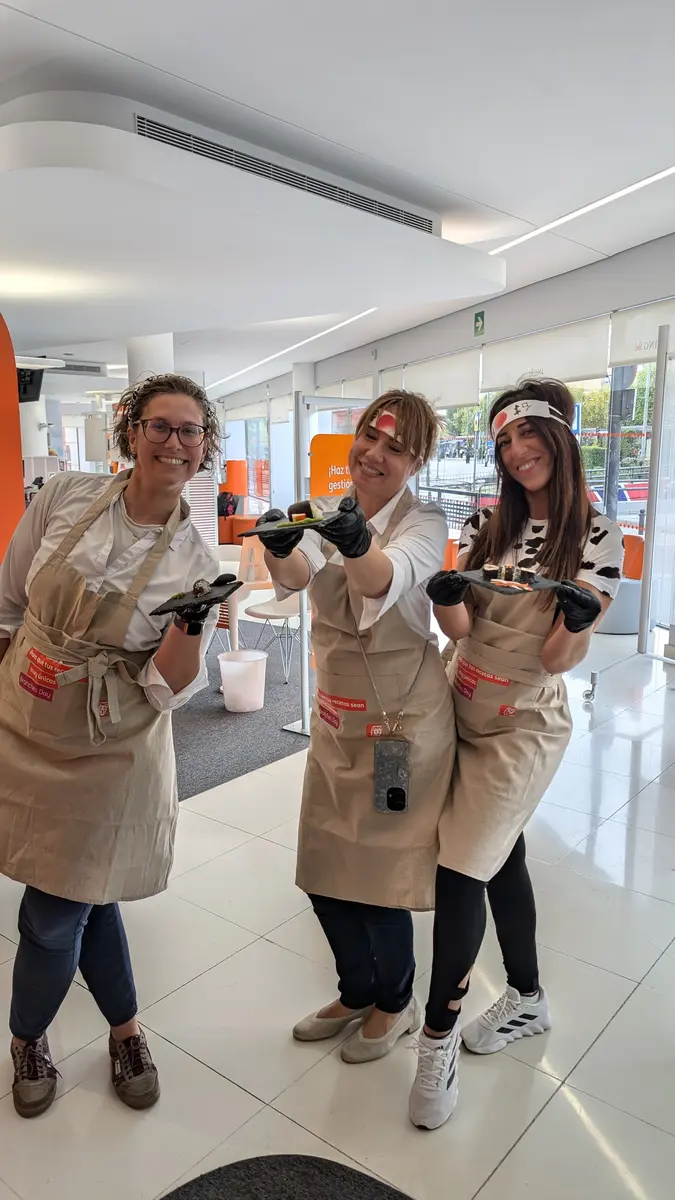 Equipo con delantales personalizados mostrando sus piezas de sushi en el taller de empresa