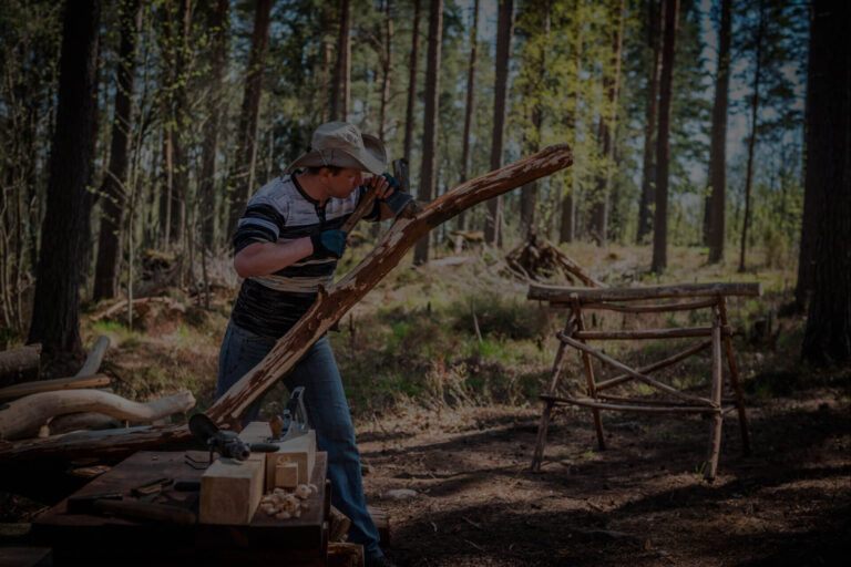 Participante trabajando la madera para construir un puente en actividad de team building outdoor en el bosque