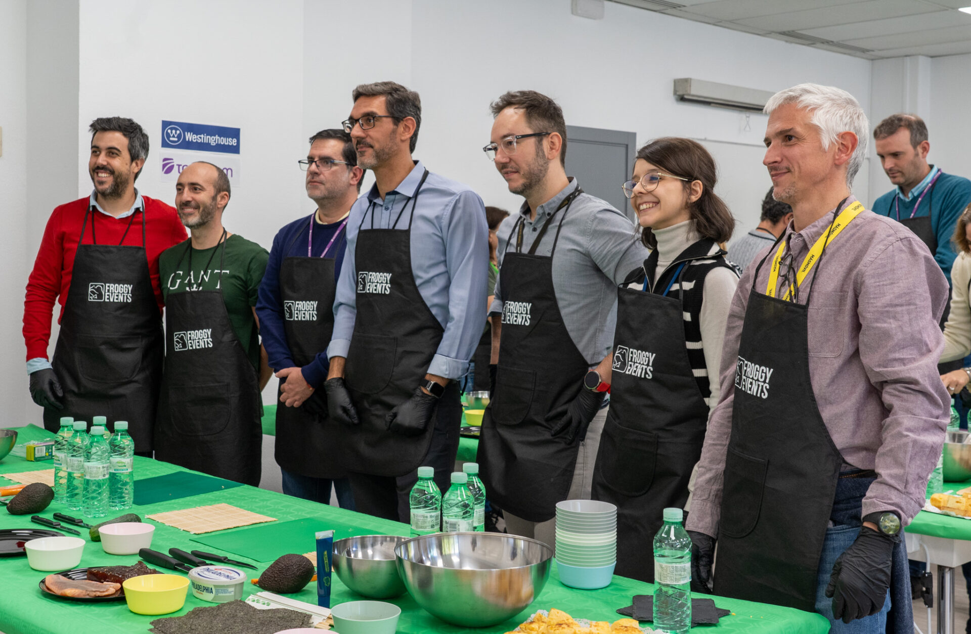 Equipo de empleados con delantales corporativos escuchando atentamente las instrucciones del chef en taller de cocina