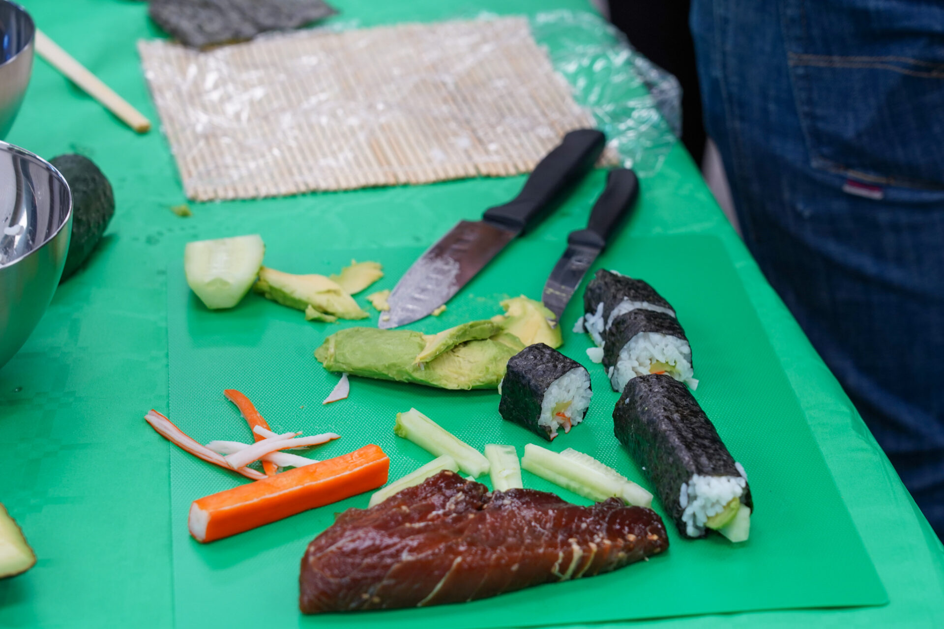 Mesa de trabajo con ingredientes frescos, esterillas y cuchillos preparados para el taller de sushi corporativo