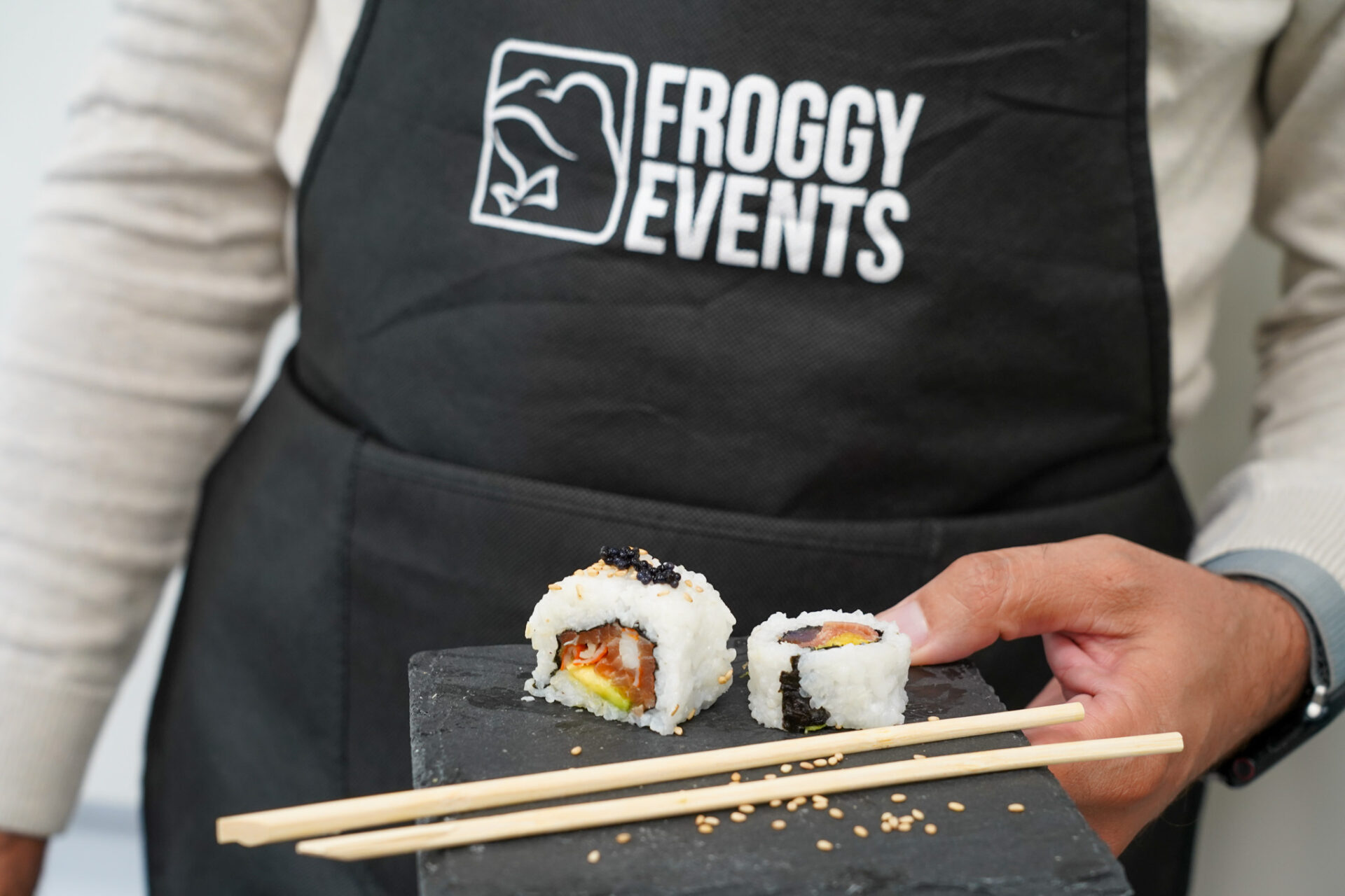 Participante mostrando un plato de pizarra con makis de salmón y aguacate recién hechos en el taller